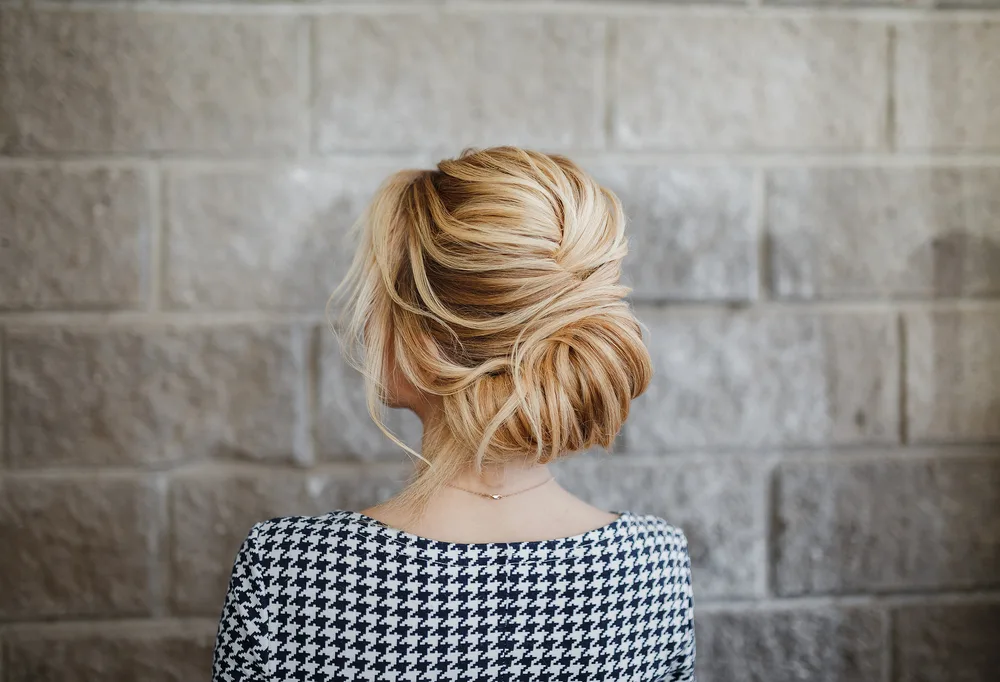 As an image for a roundup of mother of the bride hairstyles, a woman wears a Criss-Cross Low Gibson Tuck
