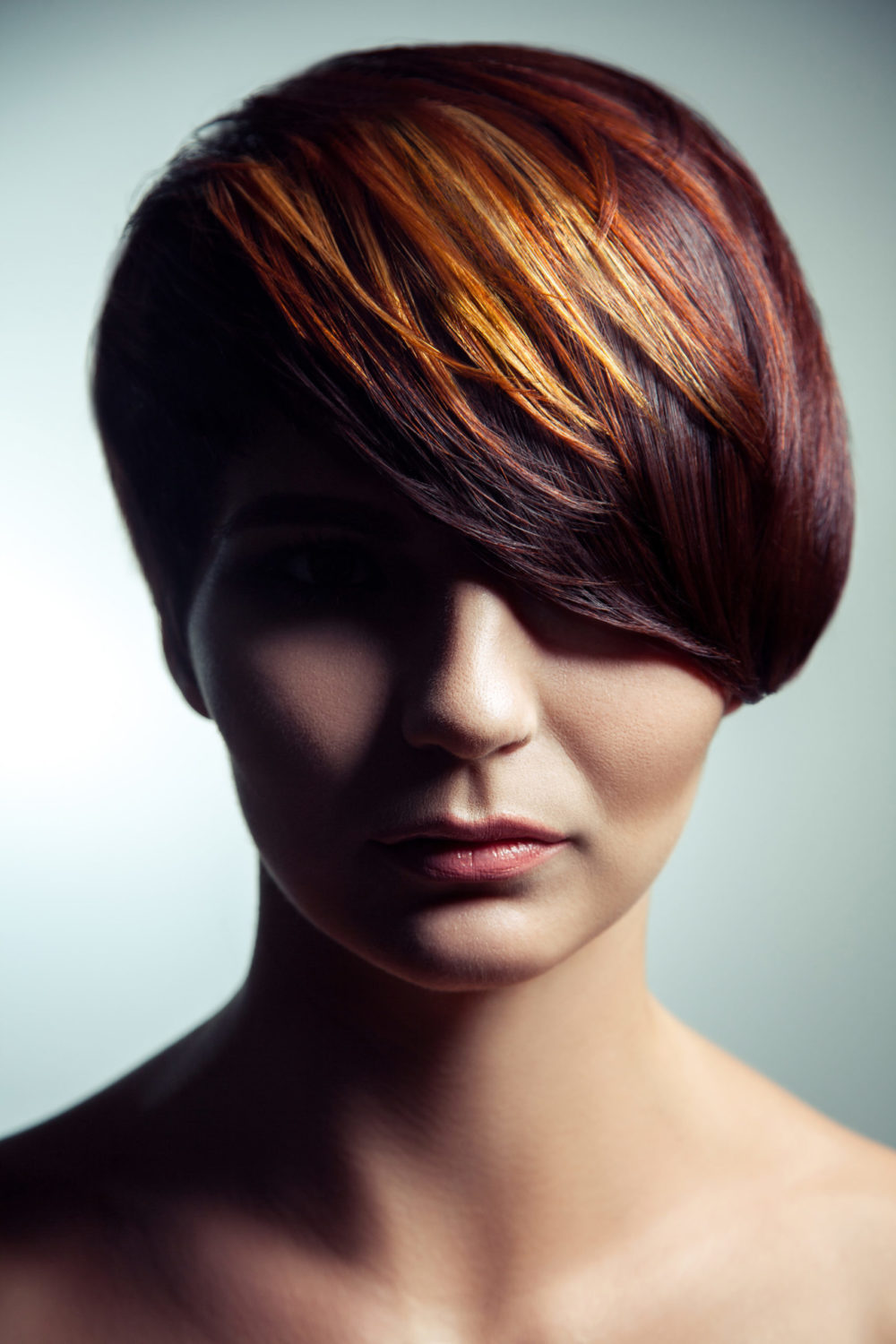 As an idea for red hair highlights, a woman wears Mahogany With Copper and Blonde Foils
