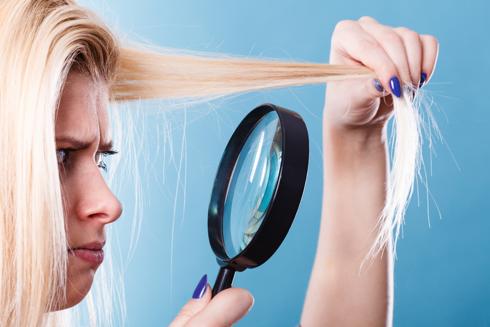 Woman looking at her damaged hair wondering what the best products for damaged and bleached hair are