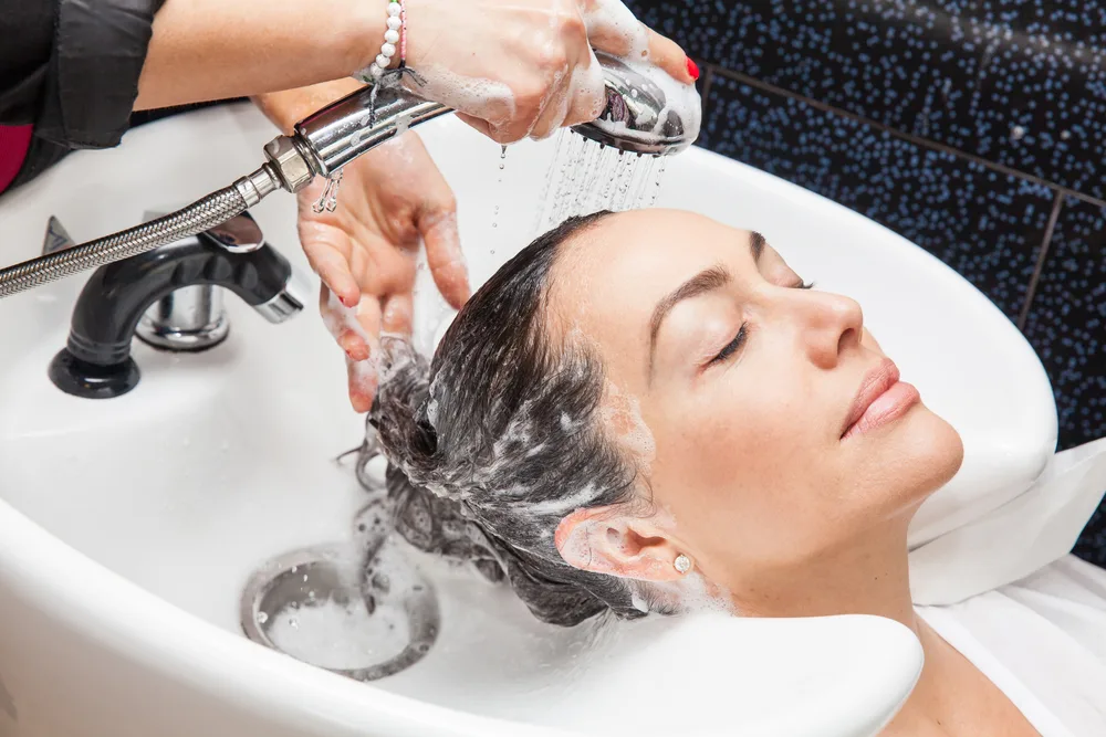 Image of a hairstylist cold rinsing hair to show her clients the benefits