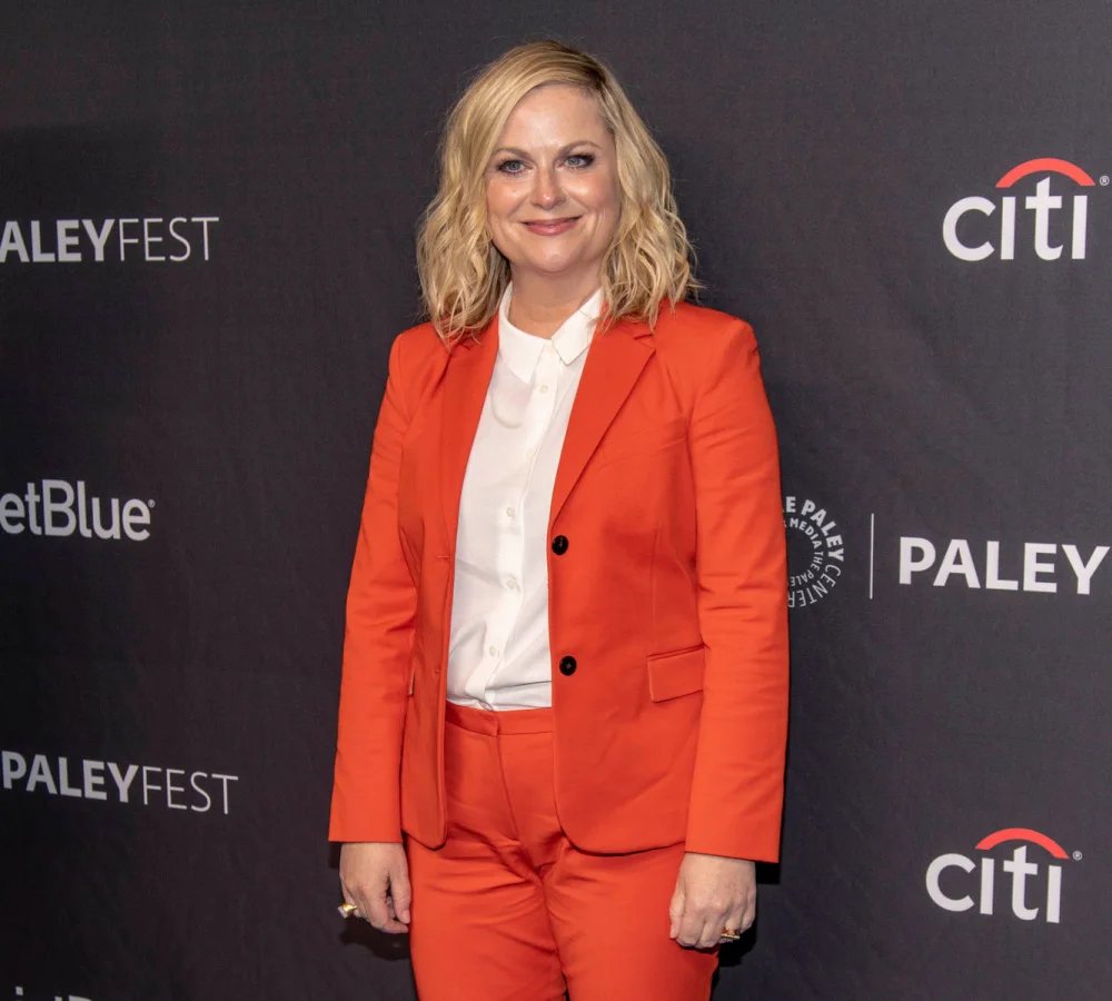 Amy Poehler on the red carpet as Leslie Knope of Parks and Recreation in an orange suit, one of the top Halloween costumes for blonde hair