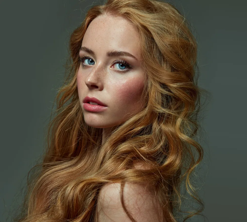 Woman glances over her shoulder with warm red hair colors in golden strawberry blonde