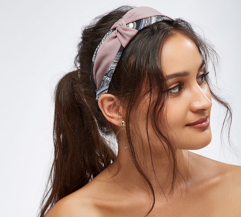 Woman with dark brown hair smiles with a fabric headband in a cute ponytail hairstyle for long hair