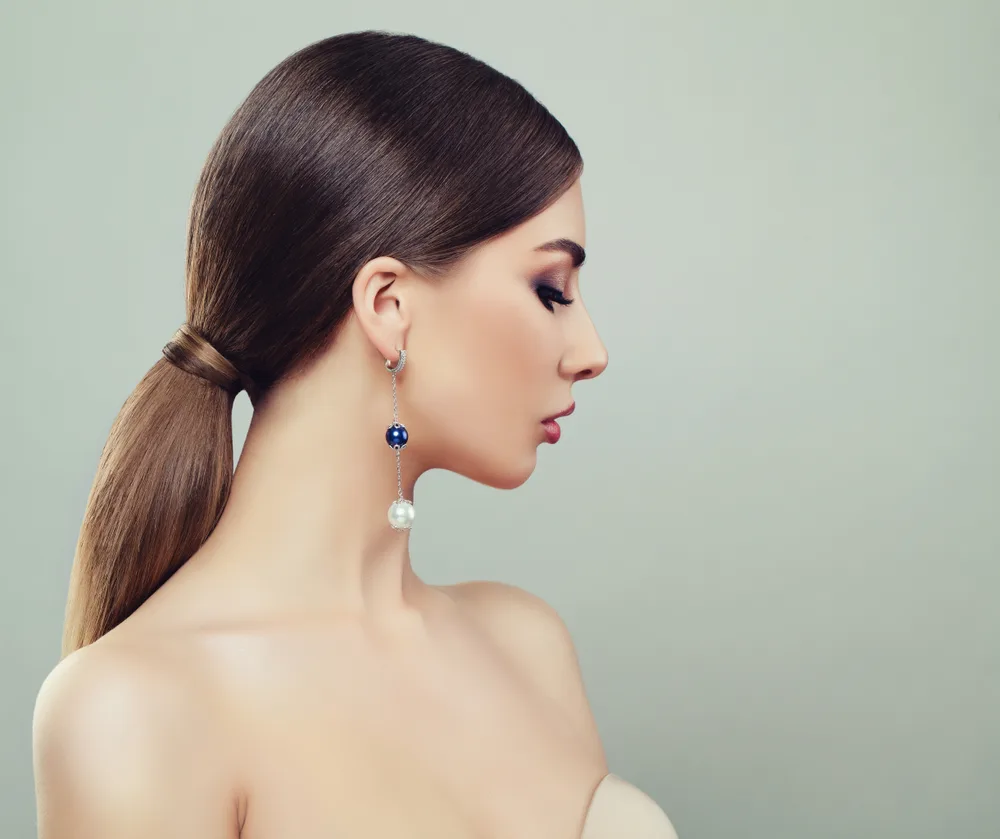 Woman turns to the side with strapless gown and shows her low ponytail as one of the many cute hairstyles for long hair