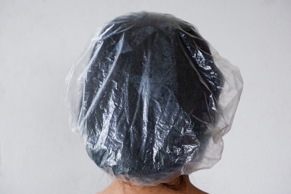 Woman wears a shower cap after using hair dye remover to get rid of black hair dye