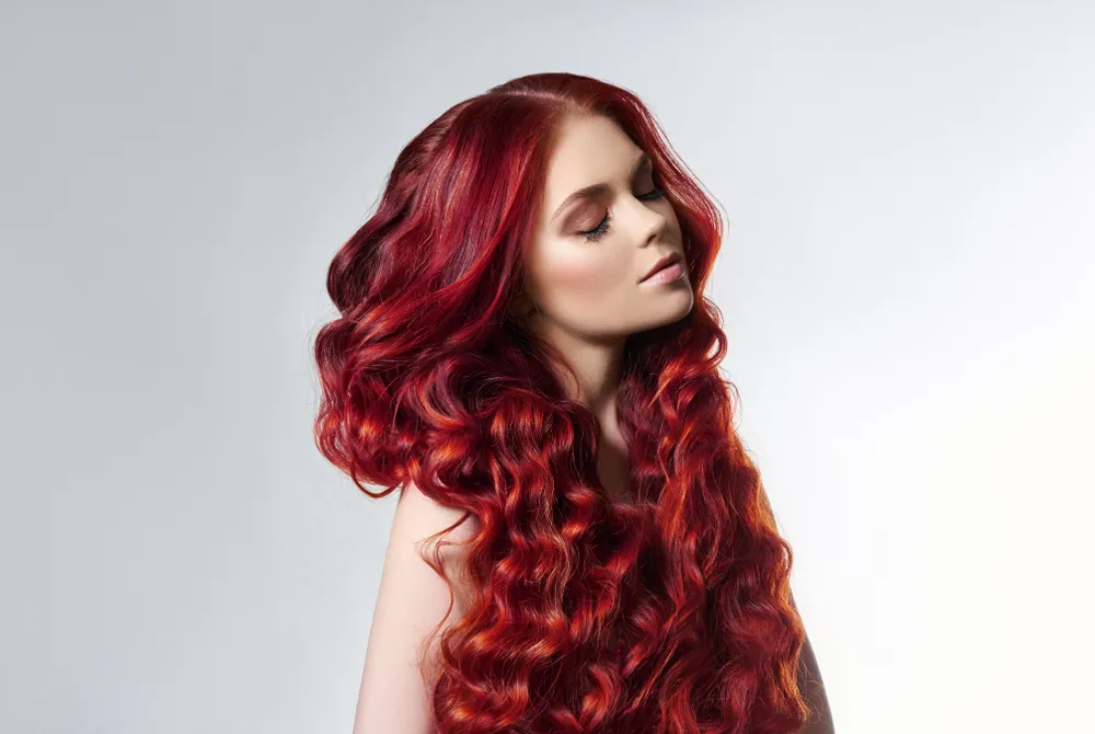 Woman with fire red balayage in a studio for a piece on the best hair colors for women with red hair