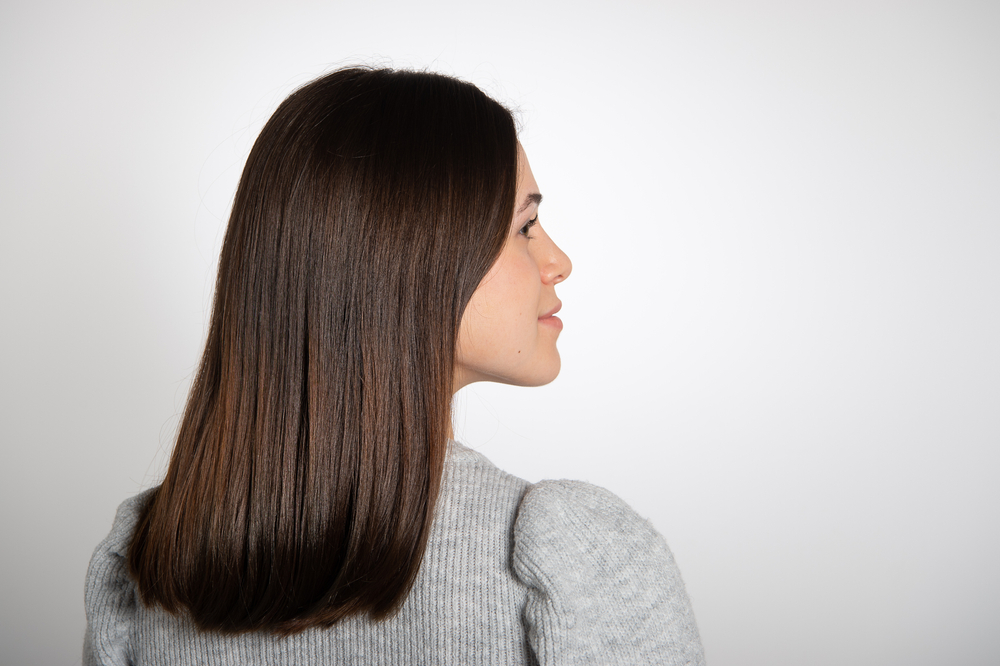Side view of woman looking to the right with chocolate dark brown hair finished with subtle chestnut color