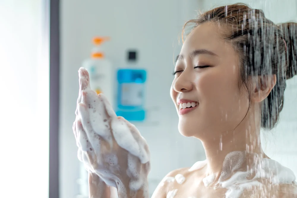 Woman holding her hands and looking at the best shampoo for Asian hair in the shower
