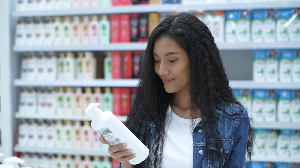 Woman looking at the best shampoo for asian hair in a store while wearing a jean jacket