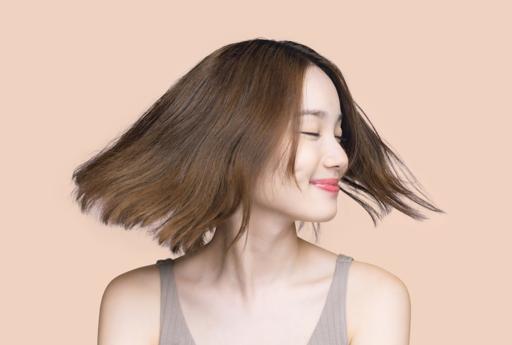 Pretty Asian woman spinning her hair in a pink studio