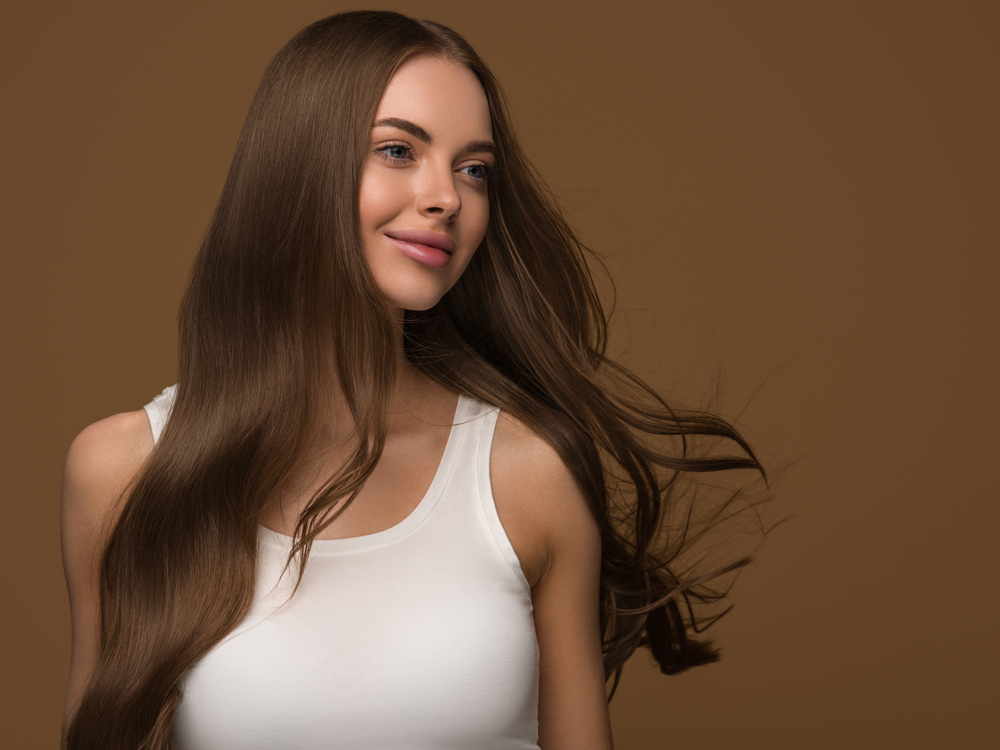 Smiling woman in white tank top wears one of our cute hairstyles for long hair with brushed glam waves