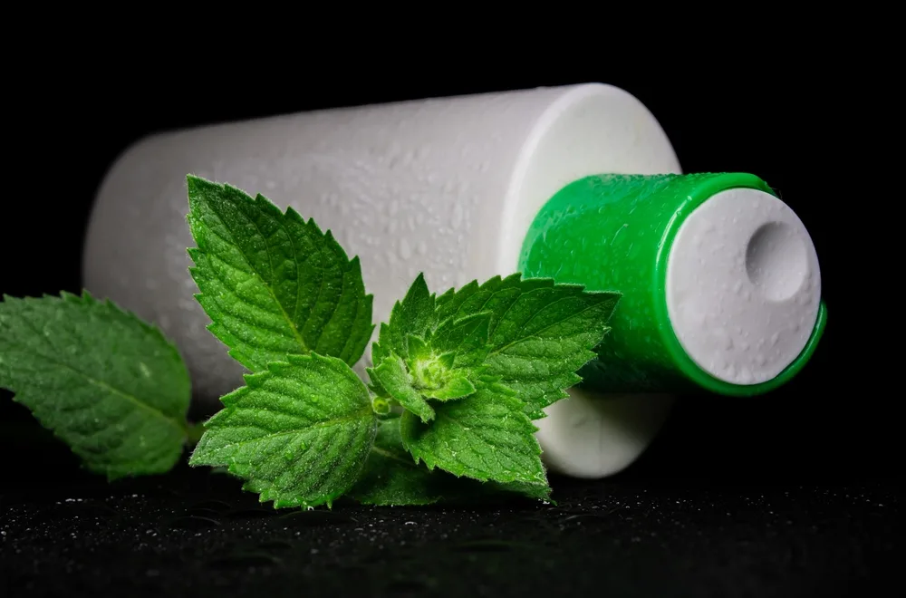 White container with one of the best shampoos for menthol pictured in a black room