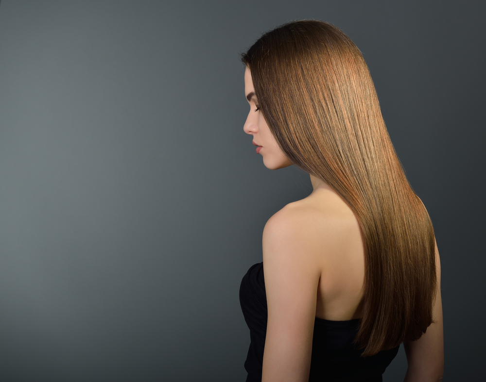 Back of woman with warm chestnut brown hair on gradient gray background