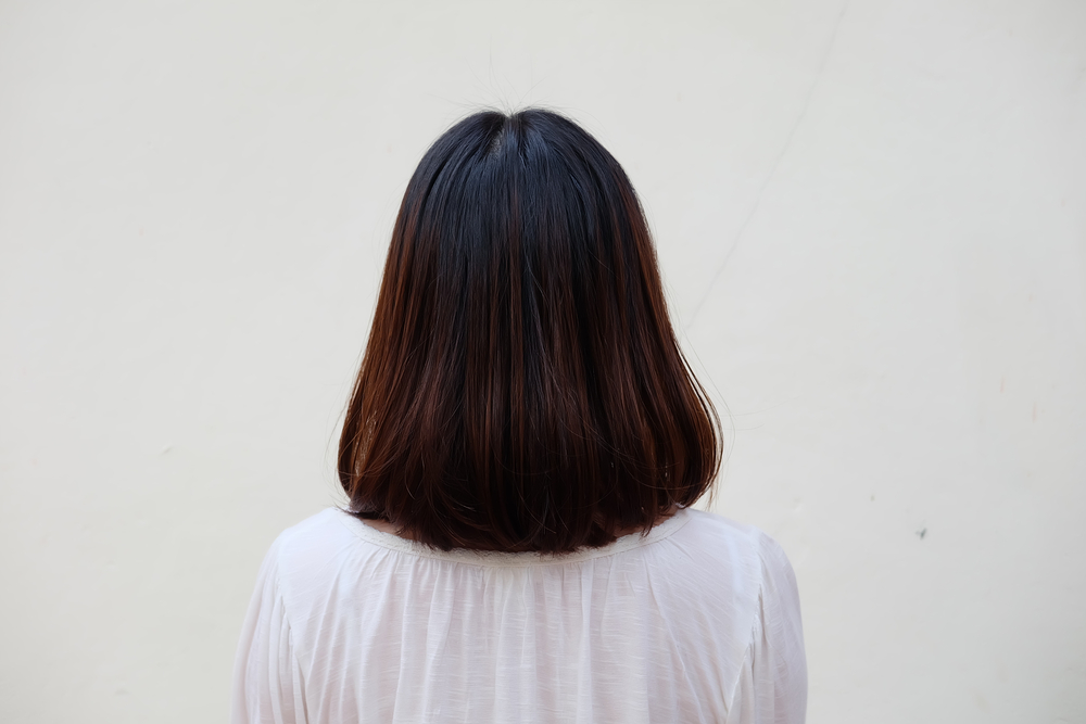 Back view of woman in white blouse with a long bob haircut in dark brown shade with black