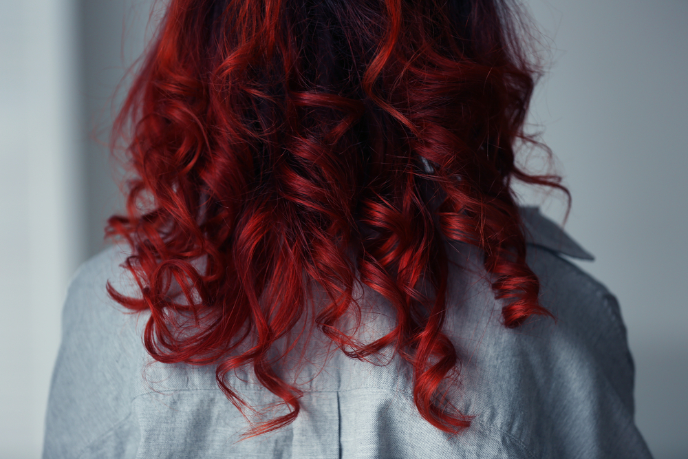 Sanguine Red hair on a woman in a jean jacket for a piece on the best colors for red hair