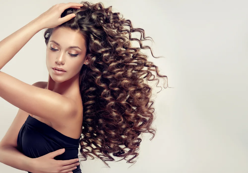 Woman with very curly hair texture wears one of her favorite cute hairstyles for long hair in black strapless top