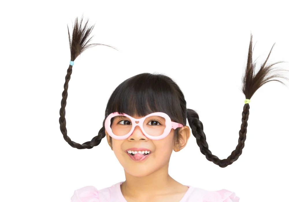 Little girl with brown hair wears braided pigtails with wire to make them stand up as one of the best crazy hair day ideas