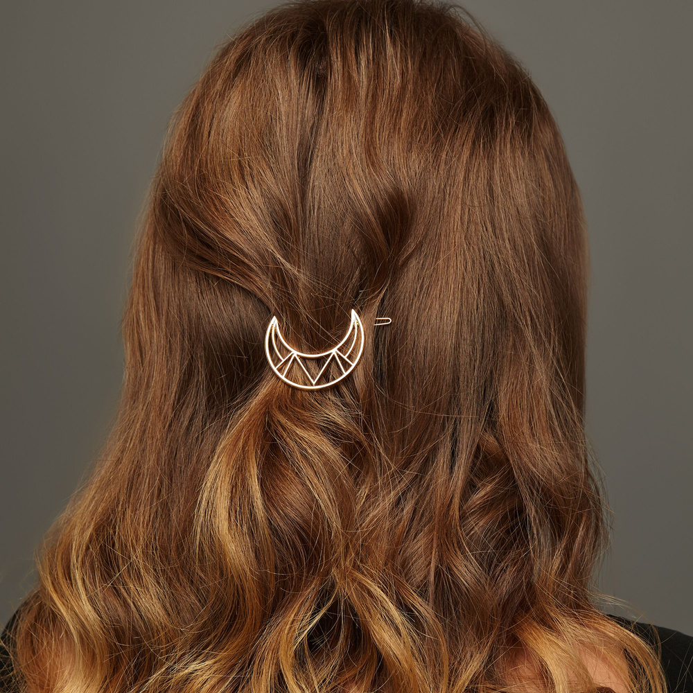 Back view close up of reddish brown hair worn in one of the top half up half down hairstyles with a crescent moon hair clip