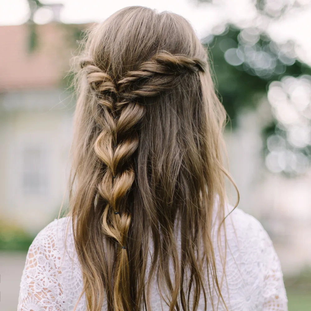 Back view of woman in white dress wearing long brown hair in half up twisted bubble braid style