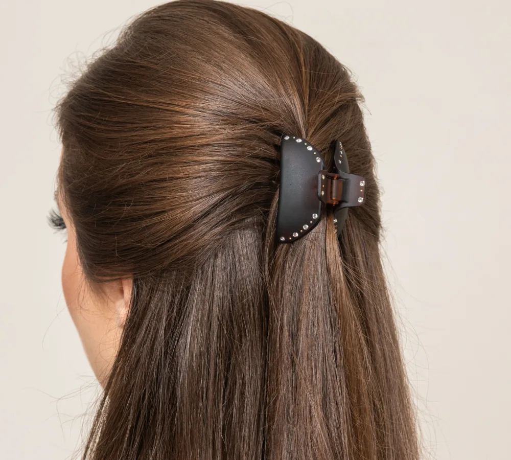 Back view of woman with brunette hair wearing a half updo style with a black leather hair clip