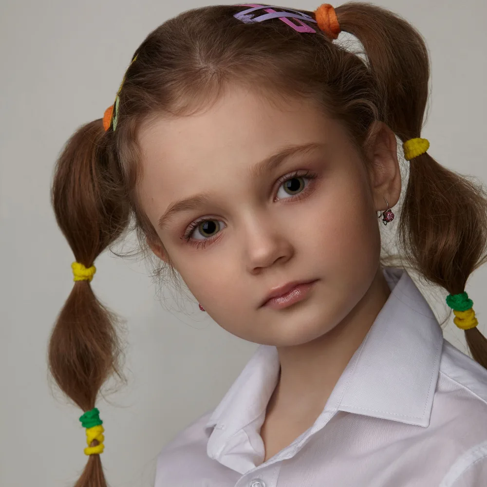 Little girl shown close up with bubble braid pigtails using colorful elastics and hair clips with collared shirt