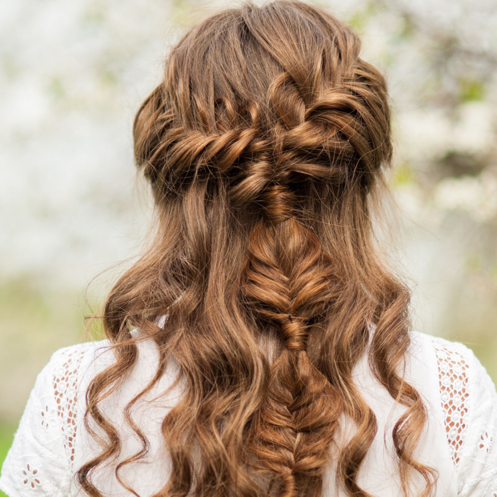 Back view of woman with auburn hair wearing half up half down braided hairstyle and white crochet top