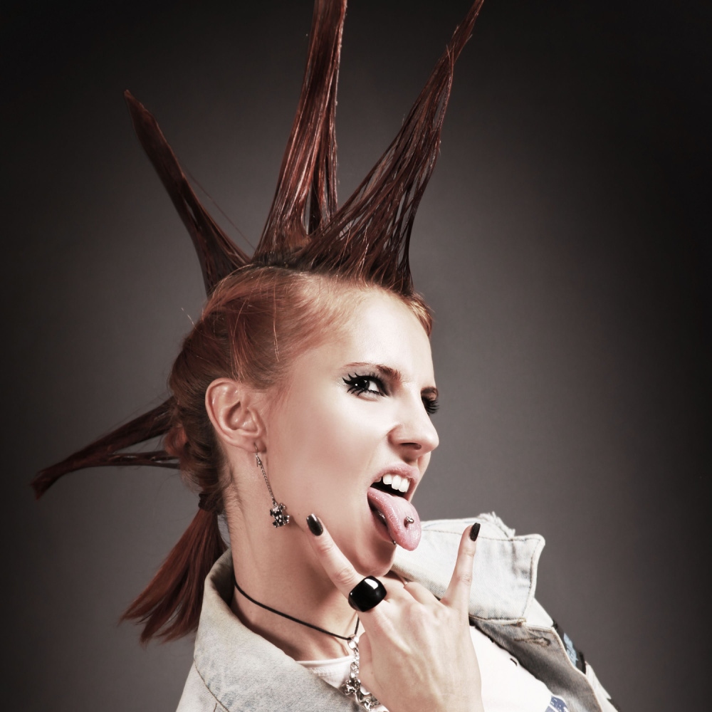 Woman with rocker vibes wears liberty spikes as one of the crazy hair day ideas with black nail polish and rocker hand symbol