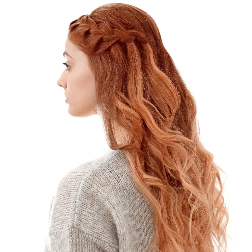 Woman with ombre red hair wears half up waterfall braids with curled ends in front of white background