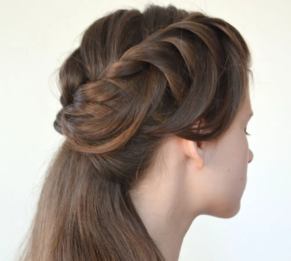 Brown haired woman seen from rear side wears half up twists hairstyle in front of white background