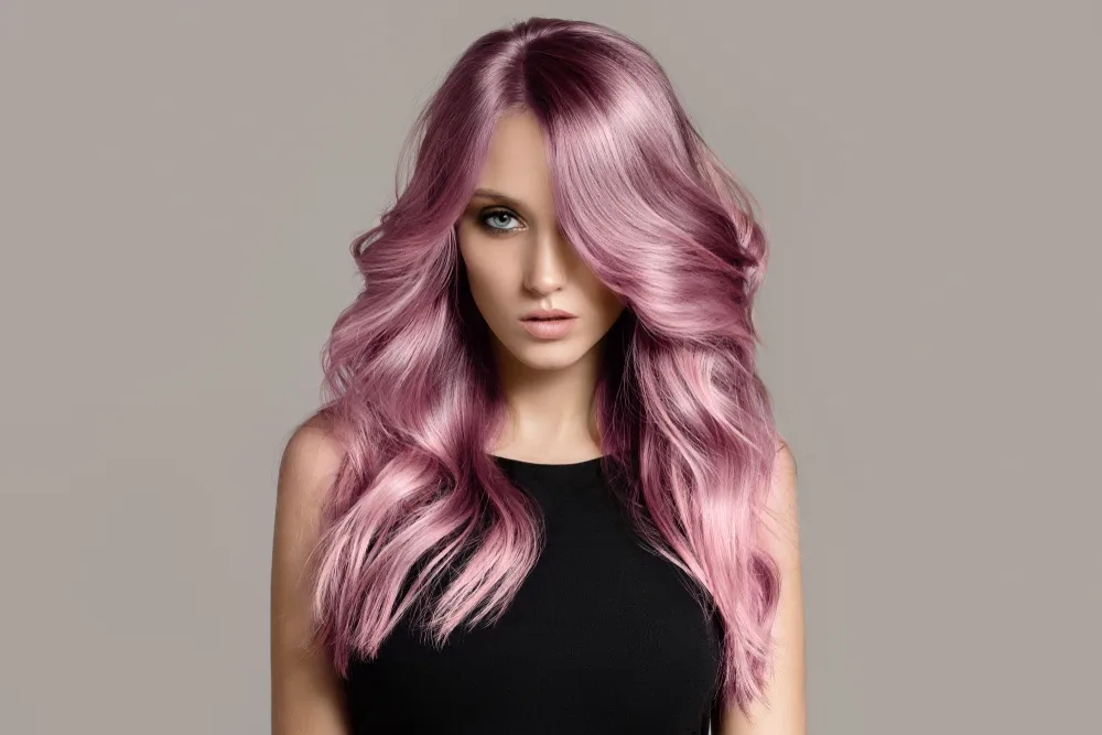 Metallic-colored light pink hair idea with silver hues on a woman looking stoic and tilting her head down