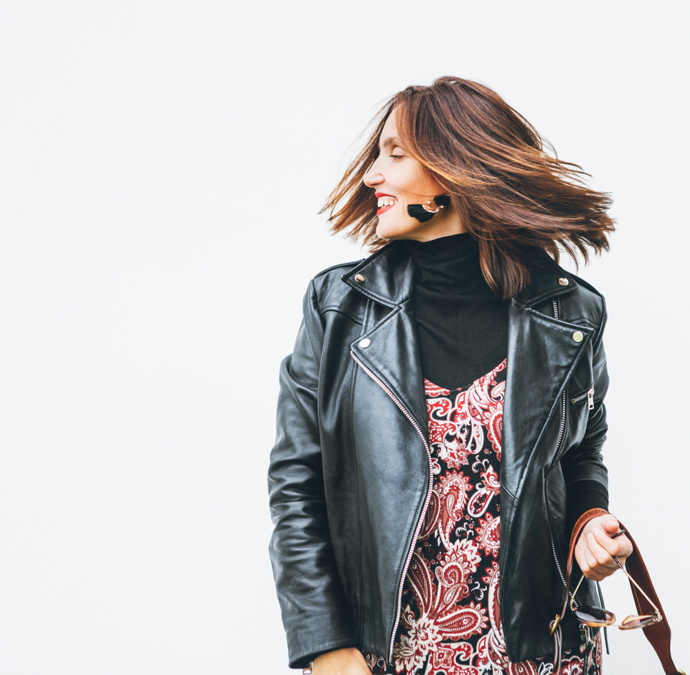Middle aged woman wears leather jacket and dress with medium length hair depicting heart shaped face haircuts