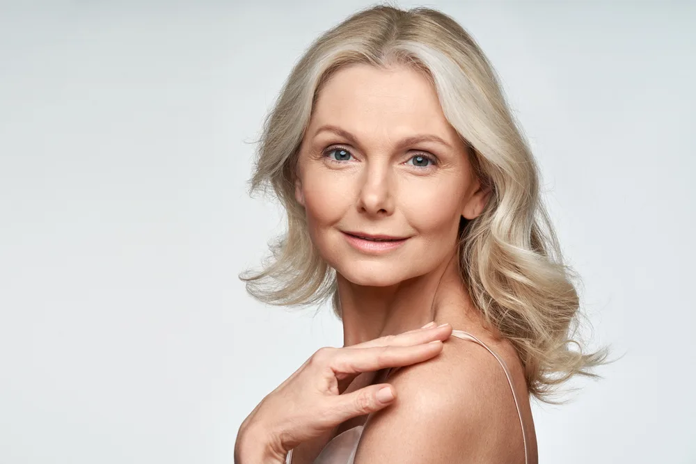 Wavy With Blended Waterfall Layers, one of the best medium length hairstyles for women over 50, on a woman in a cream silk gown