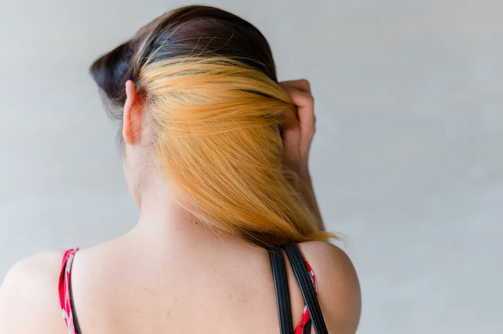 Black With Apricot Blonde Underdye on a woman in a red and black tank top