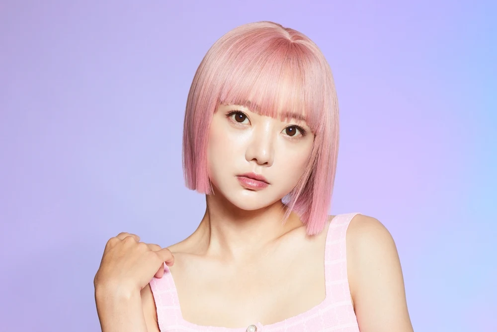 Light Bubblegum Pink hair on a Korean woman with big brown eyes in a pastel purple room