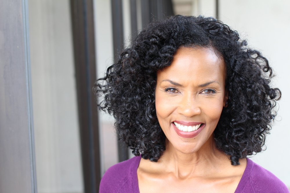 Black woman with Tapered and Defined Natural Coils pictured as an example of the best layered hairstyles for medium-length hair for women over 50