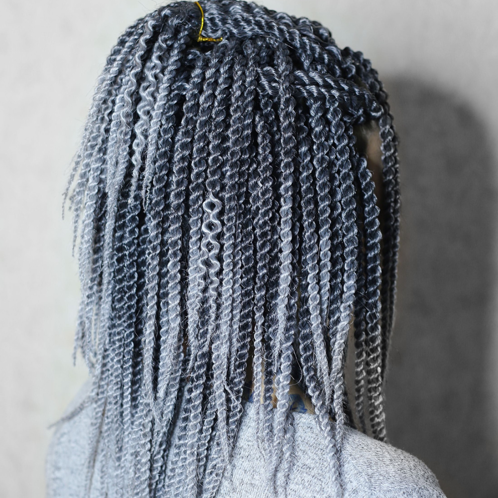 Back side view of woman with silver colored spring twist hair styled in a half updo in front of a gray wall