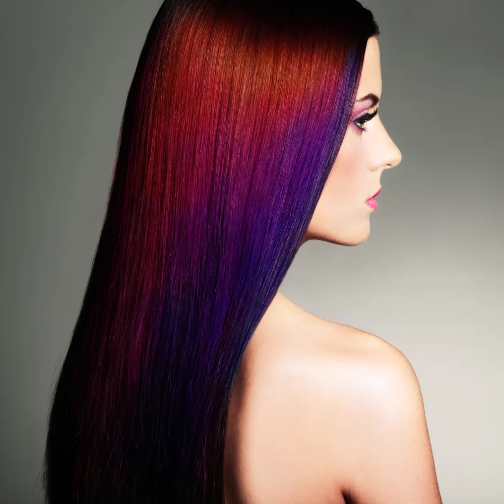 Violet Purple and Red Oil Slick Hair Color on a long-haired woman with very fair skin in a studio