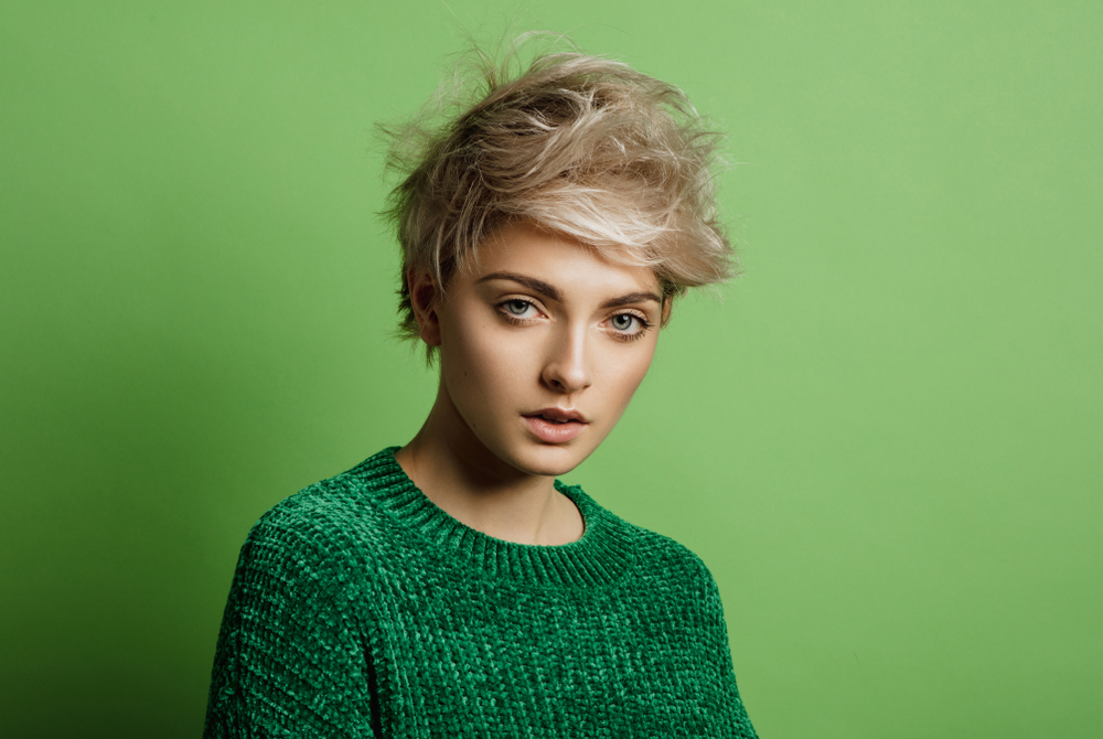 Bedhead pixie cut on a blonde tomboy in a room with a green screen