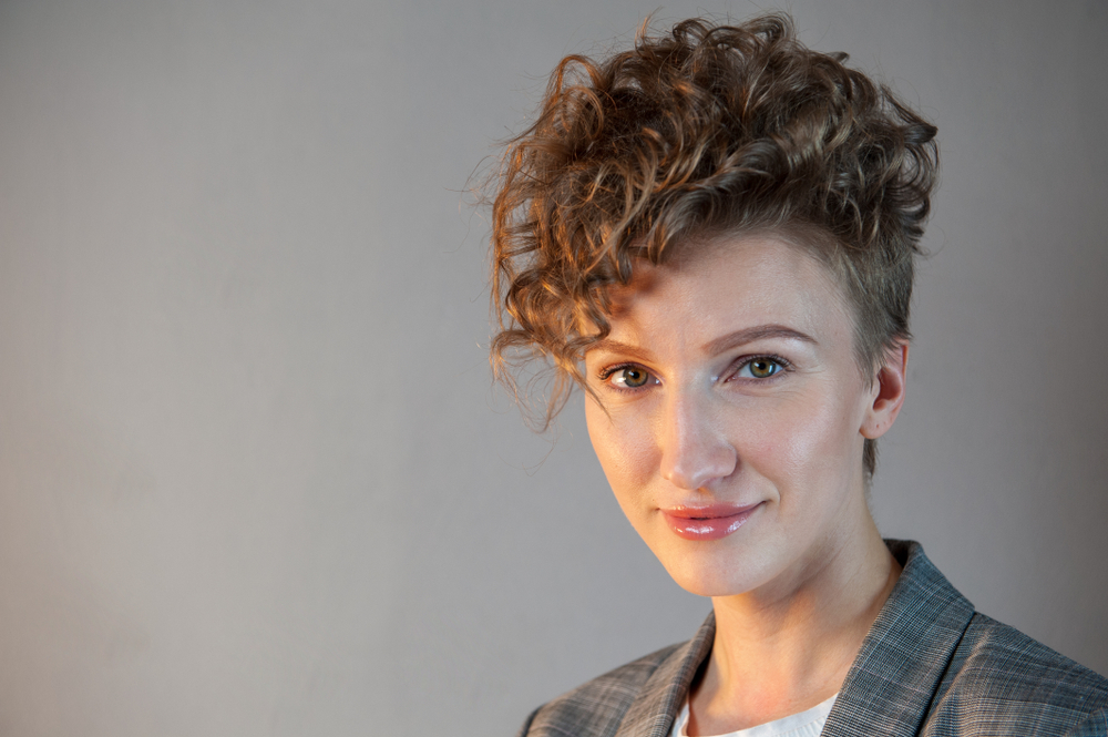 Curly pompadour haircut on a woman, a cut we consider to be one of the best short fluffy haircuts for tomboys