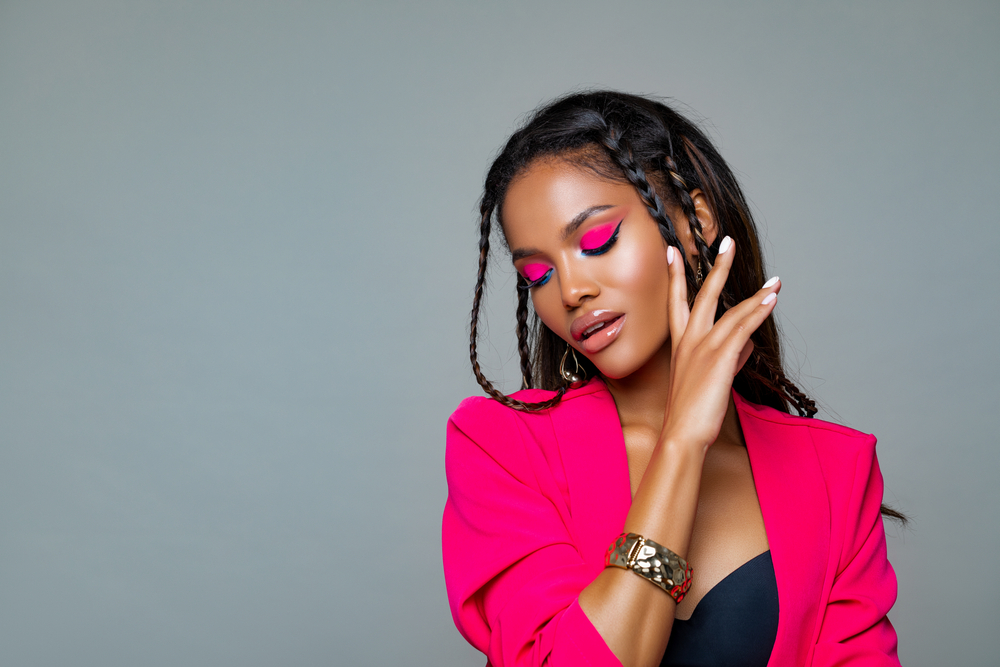 African American woman shows off cute black hairstyles for relaxed hair with trendy baby braids in a pink suit with hot pink eye makeup