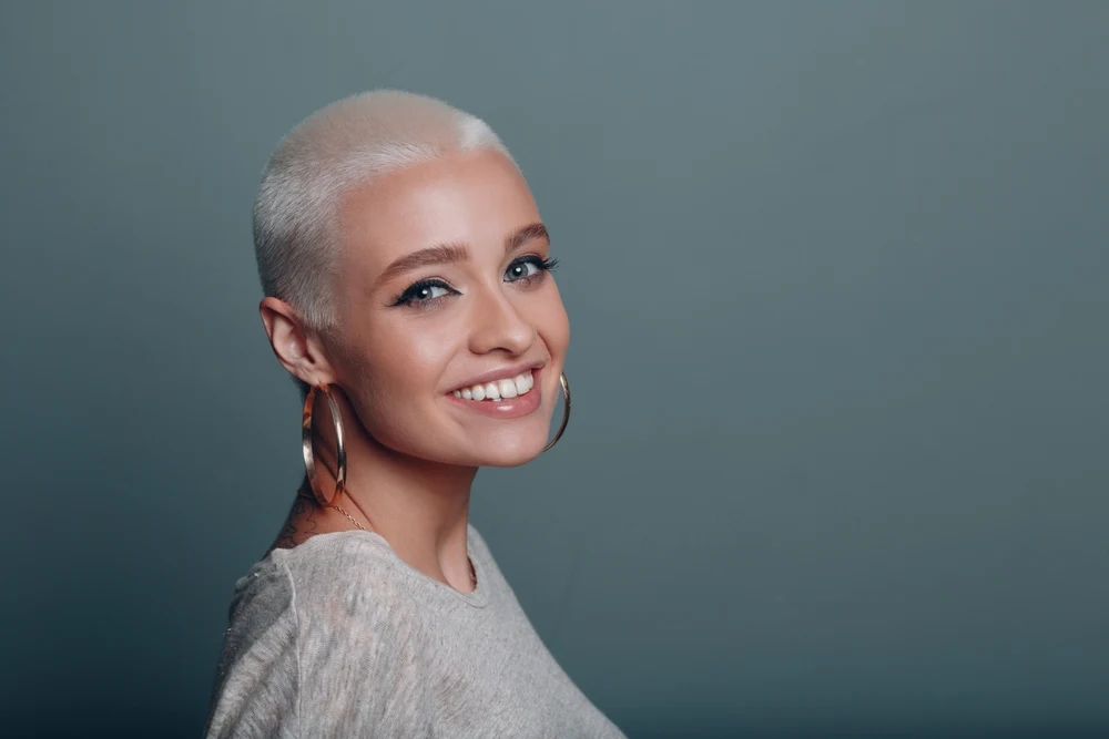 Woman with extremely short blonde hair wears the Silvery Blonde Buzz Cut