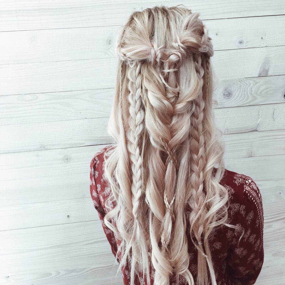 Blonde young woman wears boho braids as a half up prom hairstyle with soft waves