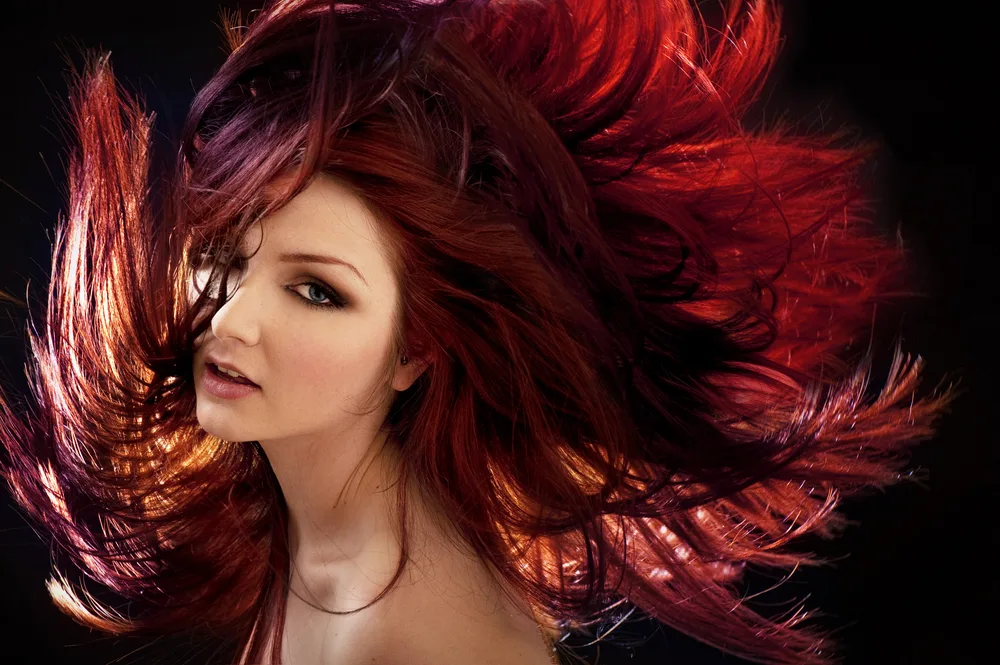 Pale woman with wild purple hair flying all over the image
