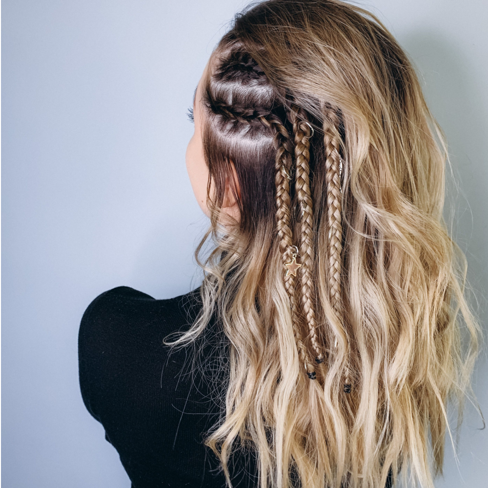 Rear view of a woman with blonde balayage curls shows off a cute hairstyle for curly hair with the sides braided back