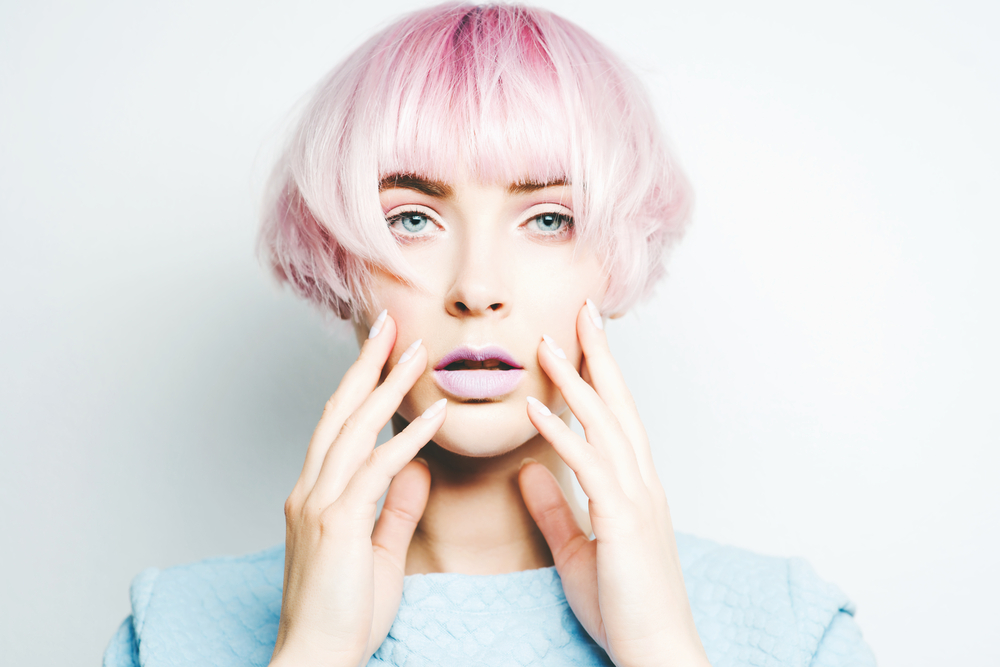 Shocked woman holds her hands on her cheeks and has pink hair styled in a mushroom cut that's listed as one of the best short haircuts for oval faces