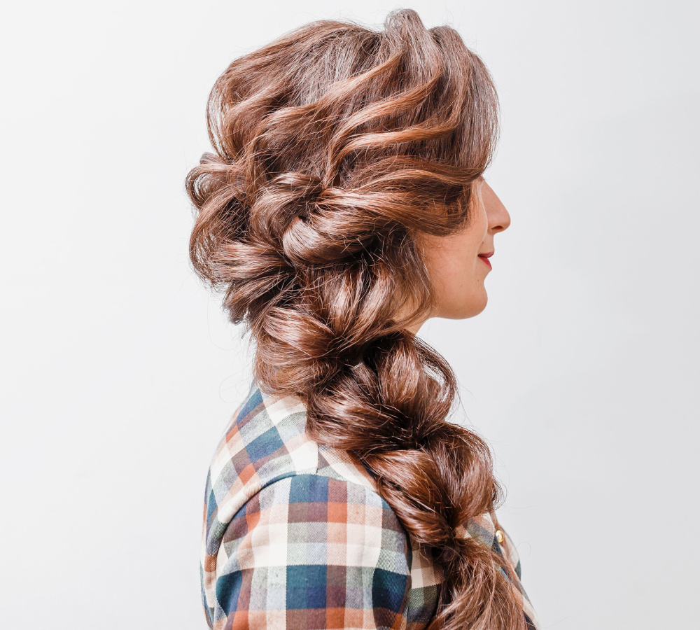 Side view of a young woman wearing a glamorous loose side braid that's perfect for homecoming hairstyles