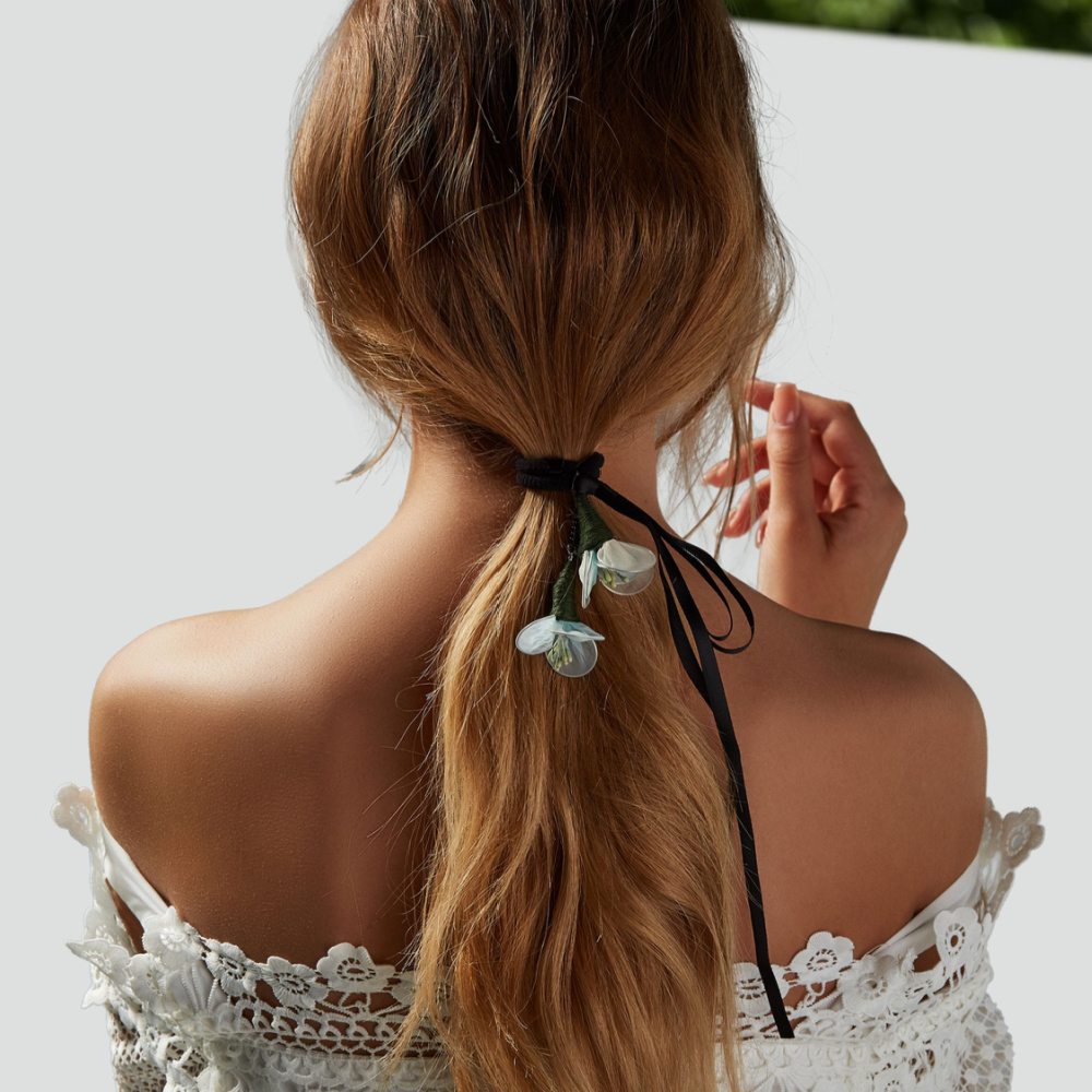 Rear view of a woman in a lacy dress sporting a cord-tied ponytail with dangling pieces as one of the best ponytail hairstyles