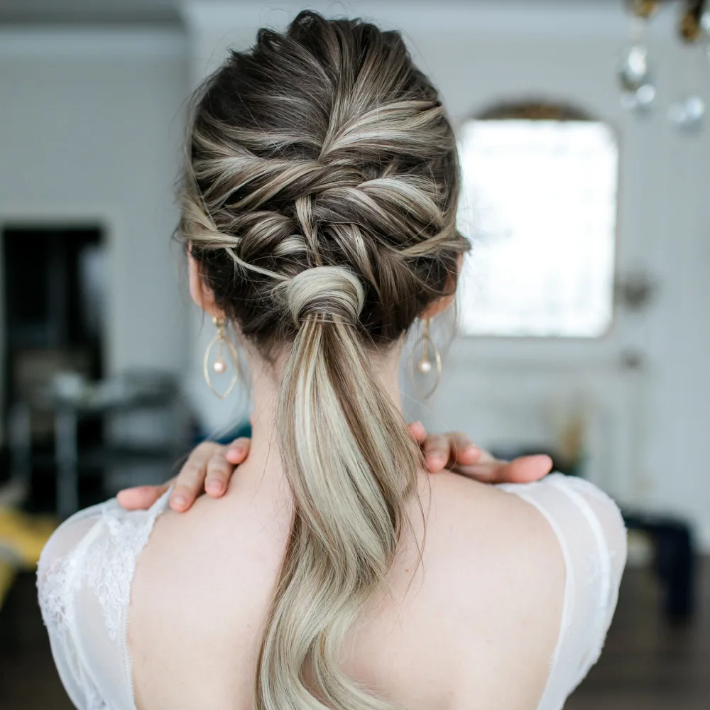 Back view of a woman's wedding look featuring one of the best ponytail hairstyles, created with braids and hair-wrapped elastic