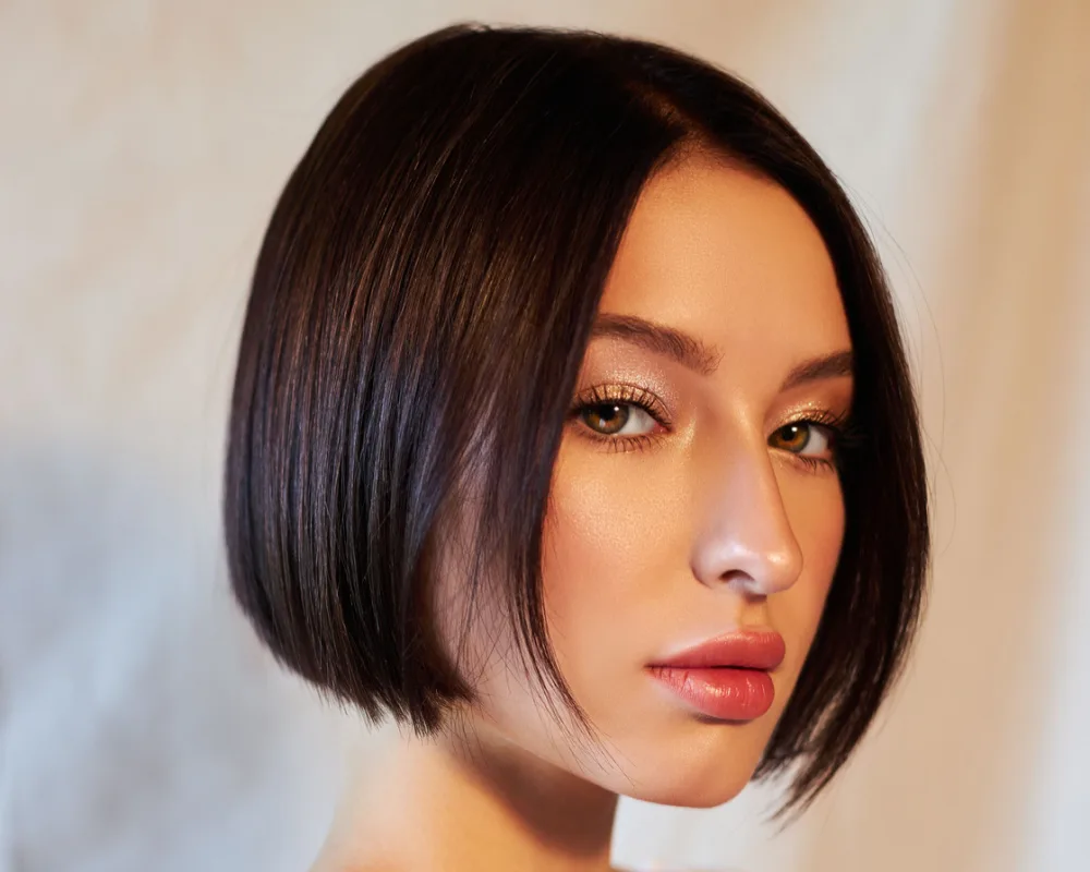 Serious brunette woman wears a chin-length bob with interior layers, a top choice for fine hair thin hair low maintenance short hairstyles for women
