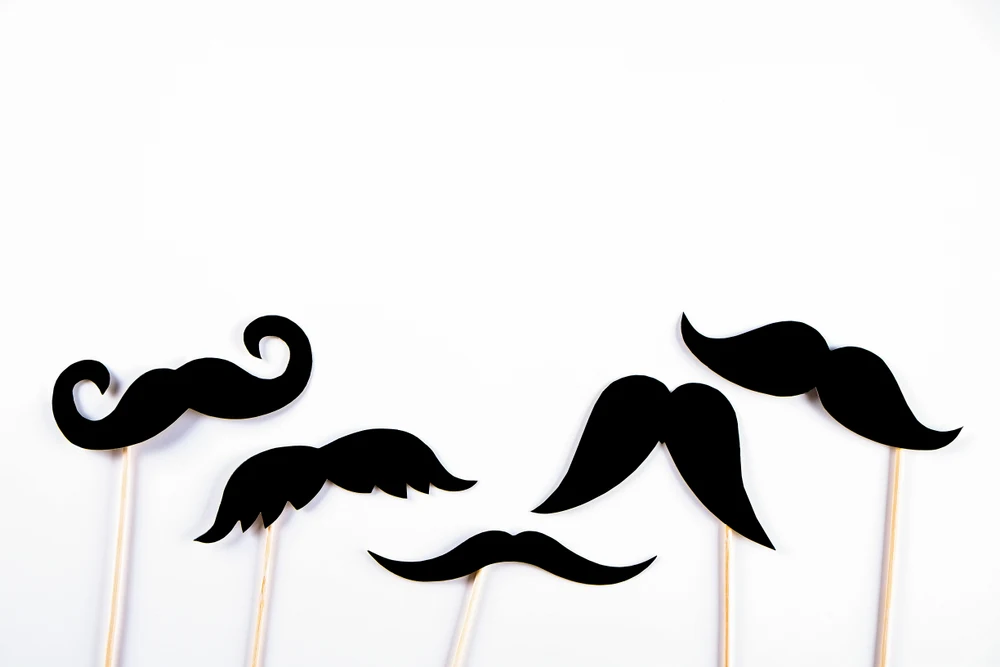 Concept of different mustache styles indicated with Photo Booth props of mustache silhouettes on sticks